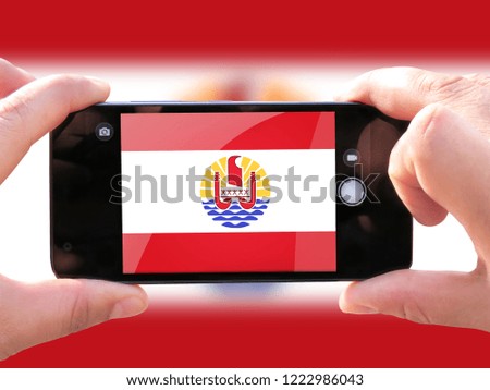 The concept of tourism and travel. The hands of men make a telephone photograph of the flag of French Polynesia. On the smartphone close-up image of the flag. Photos for social networks, blogs