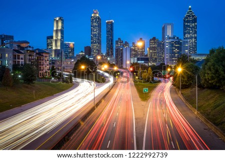 Atlanta skyline during sunset with blue skies from Jackson Street Bridge with light trails of cars during rush hour