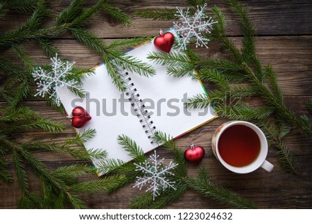 New year and Christmas festive picture with fir branches, snowflakes, tea, open notepad on a wooden rustic background