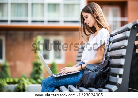 Young girl on a bench with a laptop