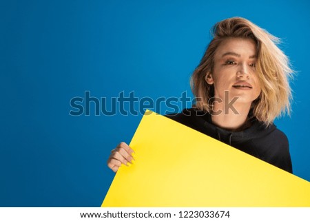 Pretty young woman displaying a yellow cardboard advertising sign. Advert copy space available
