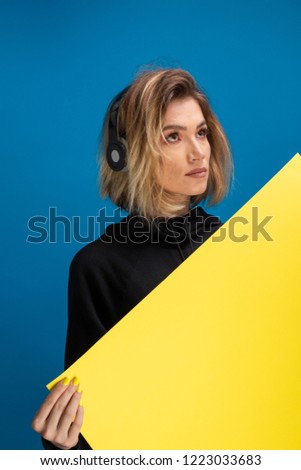 Girl wearing headphones holding a yellow card board. Poster board for advertising with copy space available