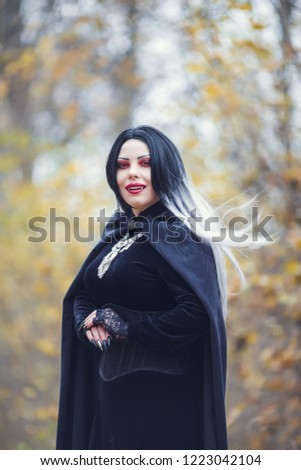 Portrait of vampire woman in black cloak with amulet