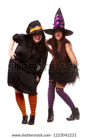 Full-length photo of two cheerful witches in hats and striped socks