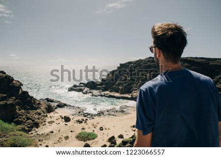 Young man with sunglasses backwards at Blow Hole Plus Creeck in Oahu landscape