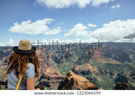 Young woman backwards with hat and long dress in Waimea Canyoy