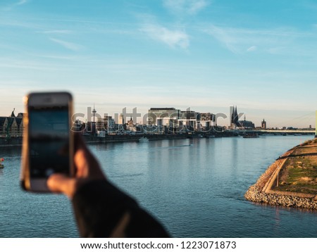 Young Woman taking pictures of Cologne's skyline with her smartphone