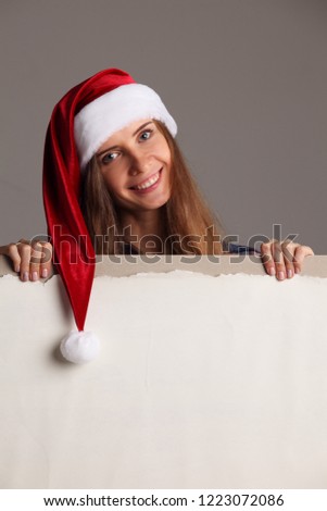 Santa girl holding blank vintage sign billboard. Christmas woman in Santa hat showing paper sign.