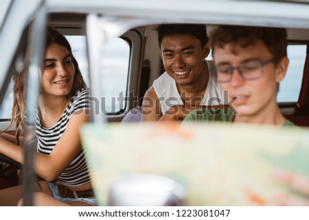 young people inside car using a map on a road trip for directions
