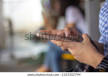 close up woman hand using smart phone outdoors side view, another girl using mobile phone in background.