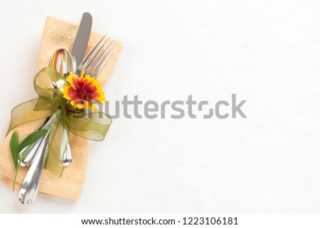 Fall Thanksgiving Table Setting with Silverware, pretty Mum Flower, and gold napking on White Damask Cloth with room or space for copy, text or your words.  It's horizontal flatlay with above view