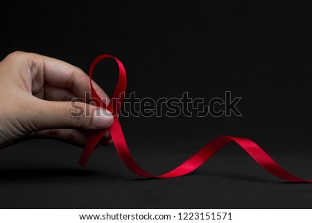 Aids red ribbon on woman's hand support for World aids day and national HIV/AIDS and aging awareness month concept Royalty-Free Stock Photo #1223151571
