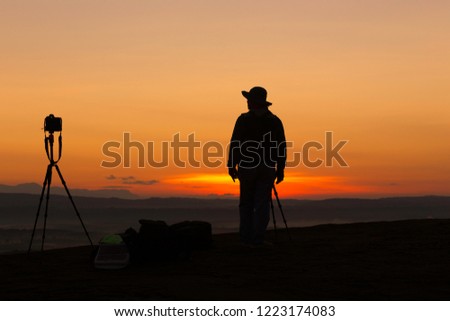 Silhouette Photographer standing  alone and camera shoots in during sunrise at Bueng Kan Hin Sam Wan  Thailand.