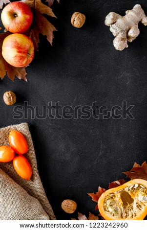 Autumn nature concept. Background with autumn symbols. Brown leaves, pumpkin, nuts and apple on black background top view copy space