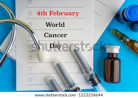 Medical syringe, stethoscope, vials, ampule and notebook with words 4 FEBRUARY WORLD CANCER DAY on blue background with selective focus and crop fragment
