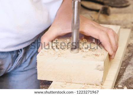 Worker drills holes in wooden templates. Manufacture of wooden toys. Close-up hands.