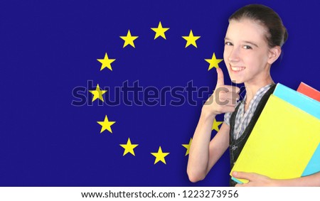 Happy young girl holding books, on the background of the flag of European Union. The concept of language learning and study. Travels.