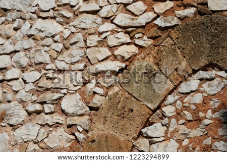 Rough surface of an ancient wall made of stone blocks and with an incorporated arch. Abstract design with curved shape. Pattern of white and grey blocks. Brown and orange colors.