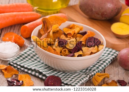 Mixed vegetable crisps on wooden table.