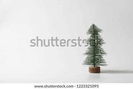Minimalist winter greeting card. Christmas and New Year miniature christmas tree on white background with copy space for text. Winter holiday celebration concept.