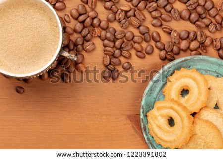 An overhead photo of coffee in a vintage cup, with coffee grains and Danish butter cookies, with a place for text