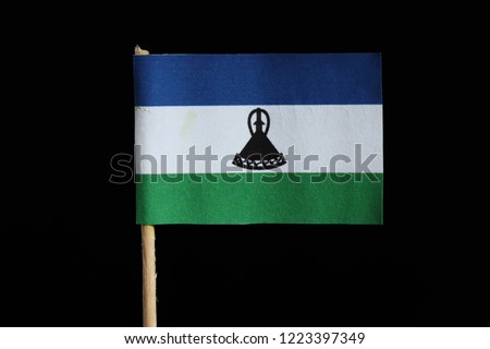 A official and original flag of Lesotho on toothpick on black background. A horizontal triband of blue, white and green with black mokorotlo centred on the white band.