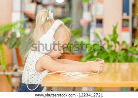 Baby girl watching cartoons on phone in headphones