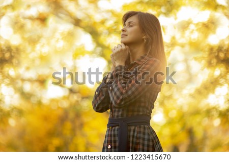 portrait of a young woman praying in nature, the girl thanks God with her hands folded at her chin, a conversation with the Creator, the concept of religion Royalty-Free Stock Photo #1223415670