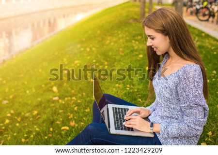 Pretty caucasian woman in casual wear professional content writer keyboarding article on modern laptop computer while sitting in park in autumn day near copy space for advertising text message 