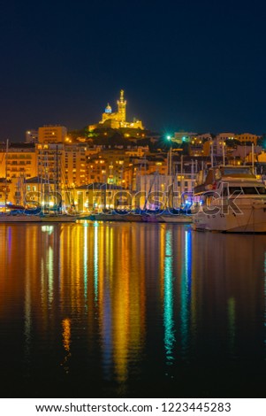 Marseille, France at night. The famous european harbour view on the Notre Dame de la Garde with colorful reflection in the water