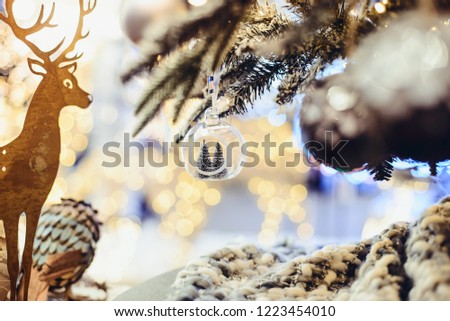 Christmas background with golden deer silhouette ,fir branches with decor and glass bulb with christmas trees inside. Christmas lights bokeh background. Vintage toning. Selective focus, copy space