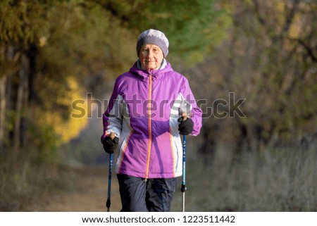 A woman over the age of 65 is engaged in Nordic walking in the fresh air