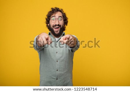 young crazy man looking angry and surprised, shouting and pointing forward, towards you