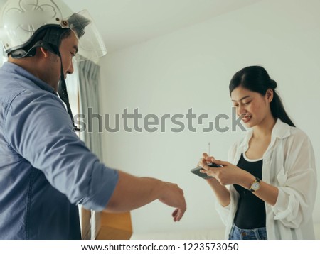 Asain woman receiving parcel from delivery man at the door.