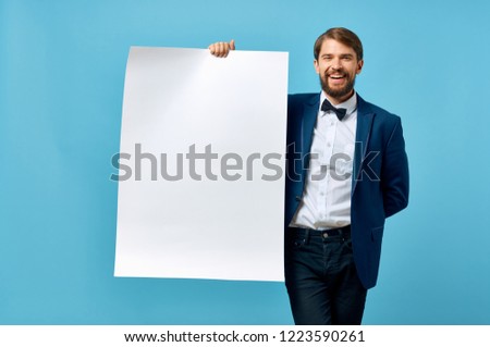 elegant man in a suit holds a white sheet of paper in his hand                       