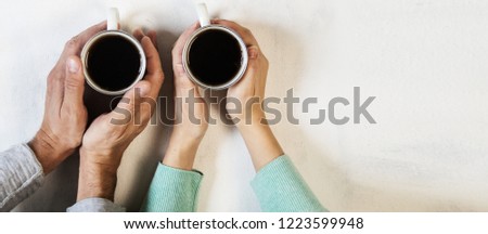 Couple in love holding hands with coffee on white marble table. Photograph taken from above, top view with copy space. Toned
