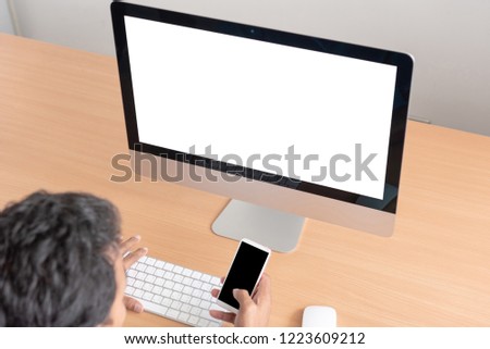 Office monitor computer, mouse on wooden table. computer and keyboard, mouse with blank screen. Digital business concept. Young man looking at empty computer screen, back view