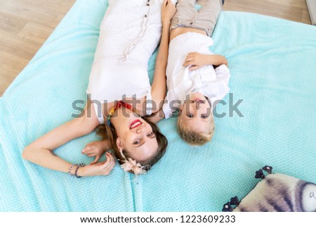 Mom and son lie on the bed and laugh. Happy childhood with fun and entertainment. Family values to spend time together, appreciate loved ones, take care of children, love parents. Beauty faces people