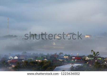 Background with dense fog and magic light at the sunrise. The coffee farm and small houses in brilliant sunshine