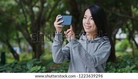 Woman take photo on cellphone in park