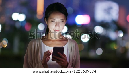Woman send sms on cellphone in city at night