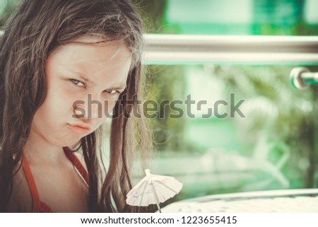 Frowning girl holding an umbrella from cocktail near her face