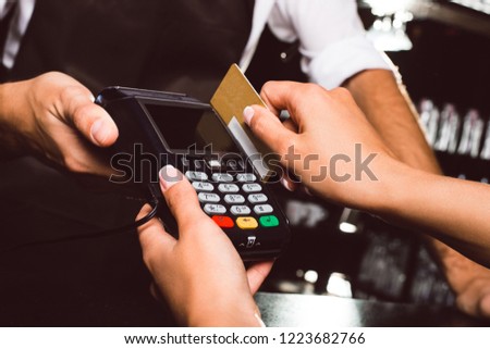 In one simple touch! Close up of woman paying with a credit card and credit card reader
