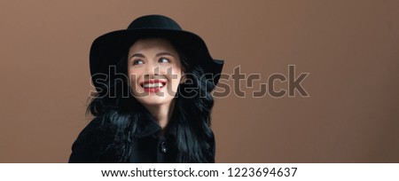 Beautiful young woman in a fashionable coat on a brown background