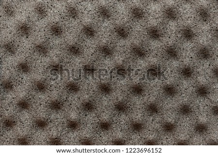 Gray background of foam material with pyramidal protrusions on the surface used for vibration and noise insulation in recording studios or cars