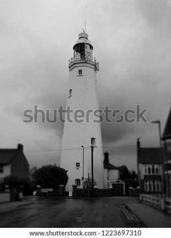 Withernsea Lighthouse, an inland lighthouse that stands in the middle of the town, taken on a stormy day with dark clouds and set against the background of blurred houses, shot in monochrome, UK