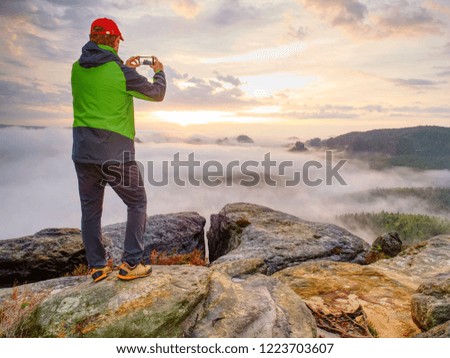 Hiker travel alone, take and share photos from outdoor trips.  Fall nature within misty morning. Photographer taking picture of tropical forest, sky and clouds