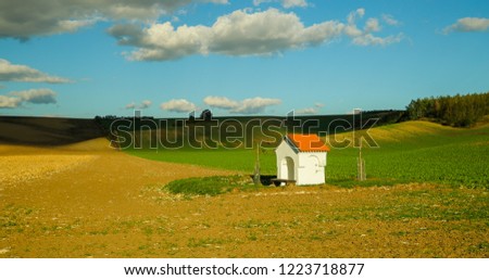 A field with a small church that invites to relax during a sunny