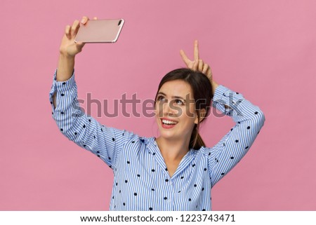 Beautiful, happy and smiling female making a selfie. Brunette holds the smartphone in hand
