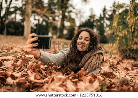 Girl making selfie in autum park.